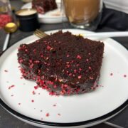 A slice of moist chocolate cake on a white plate.