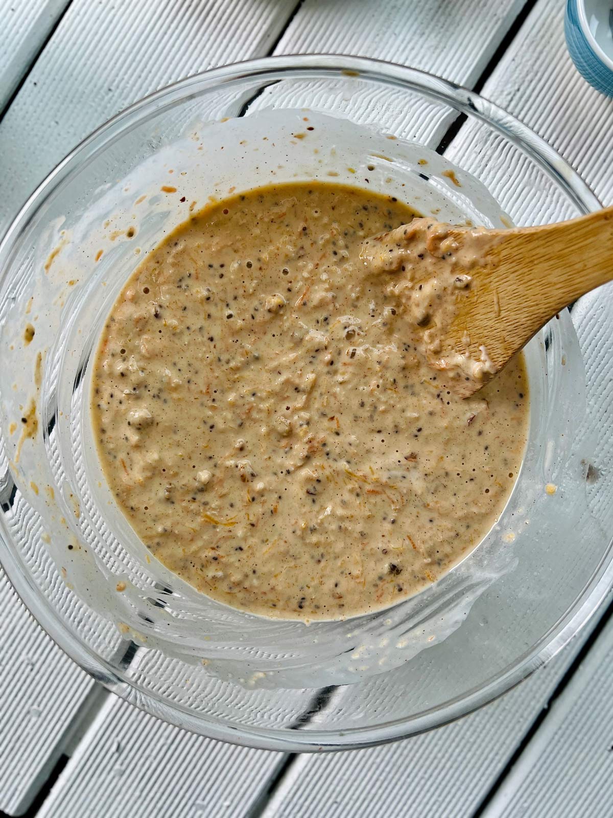 Batter for butternut squash pancake ready to go to pan in a glass bowl with wooden spatula tucked in