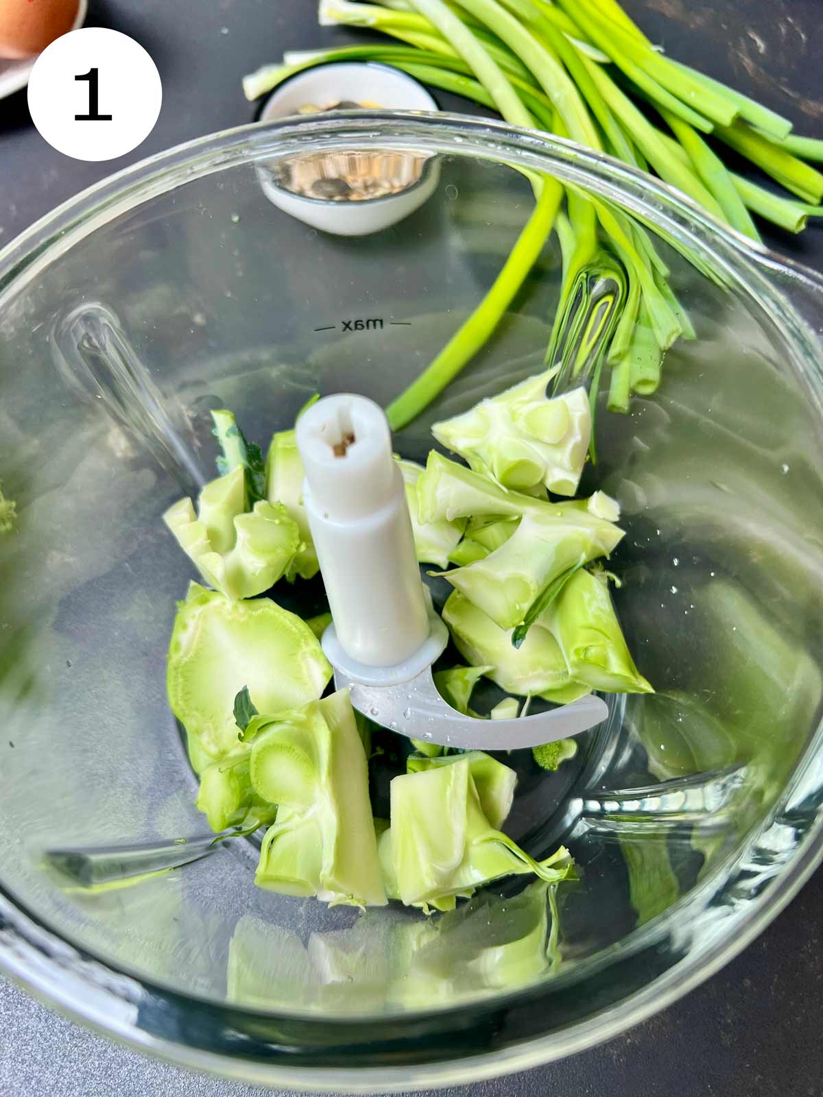 Broccoli stalks in a glass bowled blender.