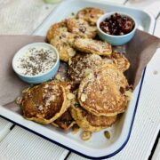 Butternut squash pancakes on white tray with the blue dream with two serving dishes, one with jam, one with yoghurt and chia seeds sprinkled over