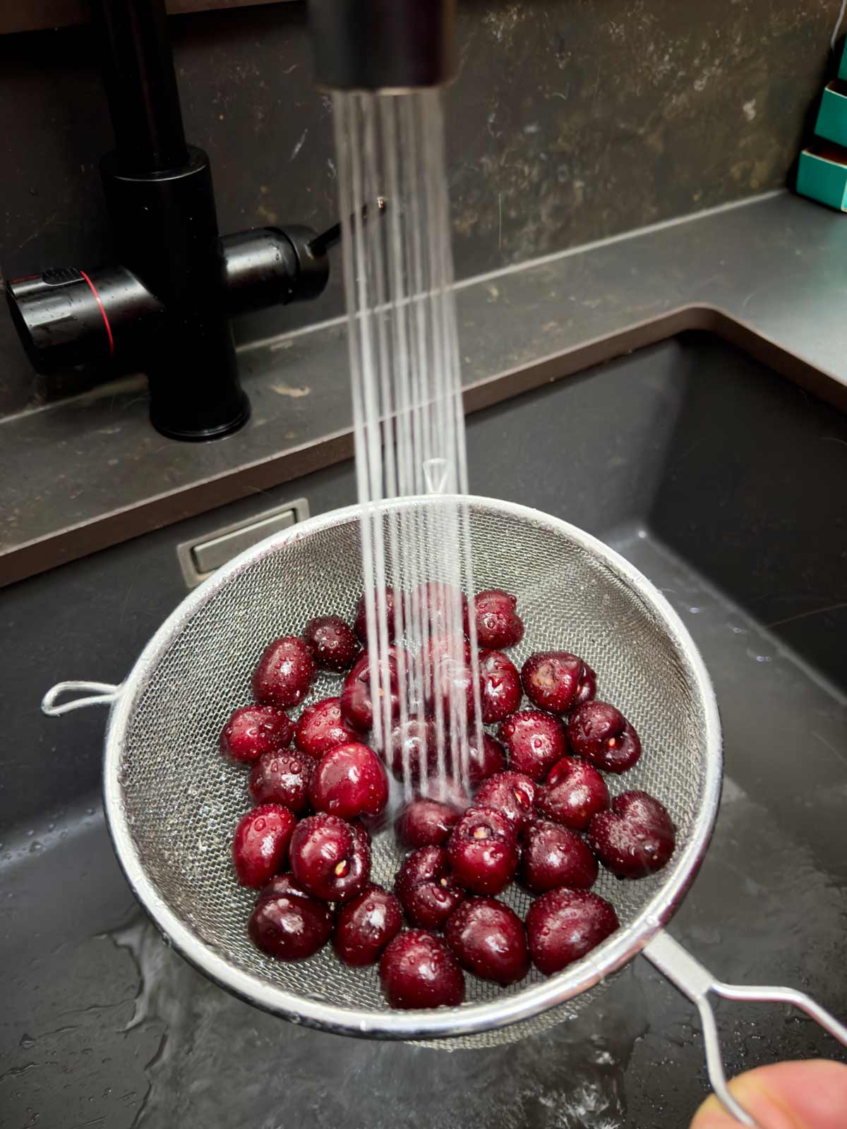 Cherries being washed in a colander.