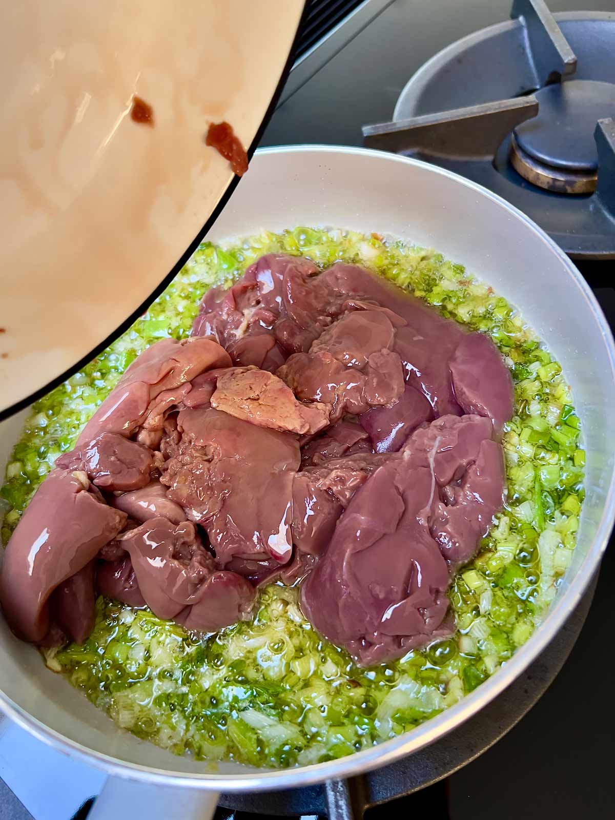 Chicken livers in a pan with cooked scallions/spring onions.