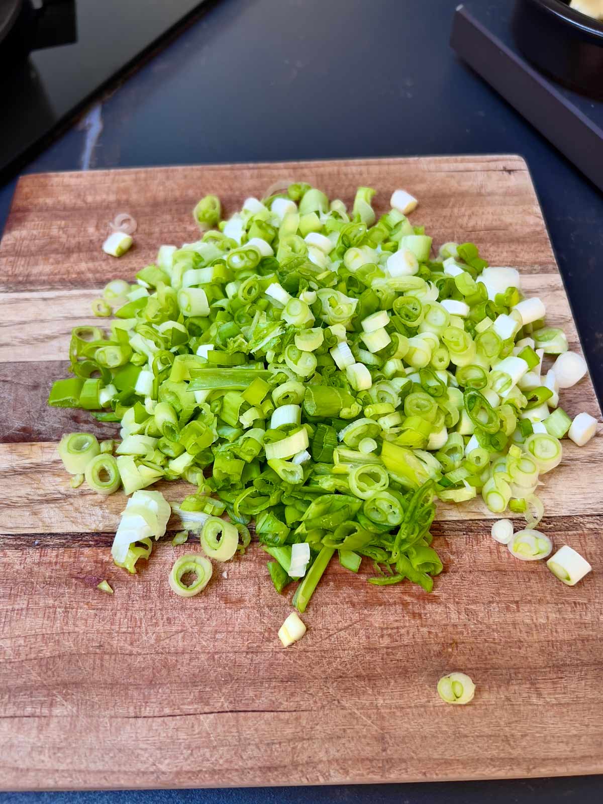 Chopped scallions on a wooden chopping board.