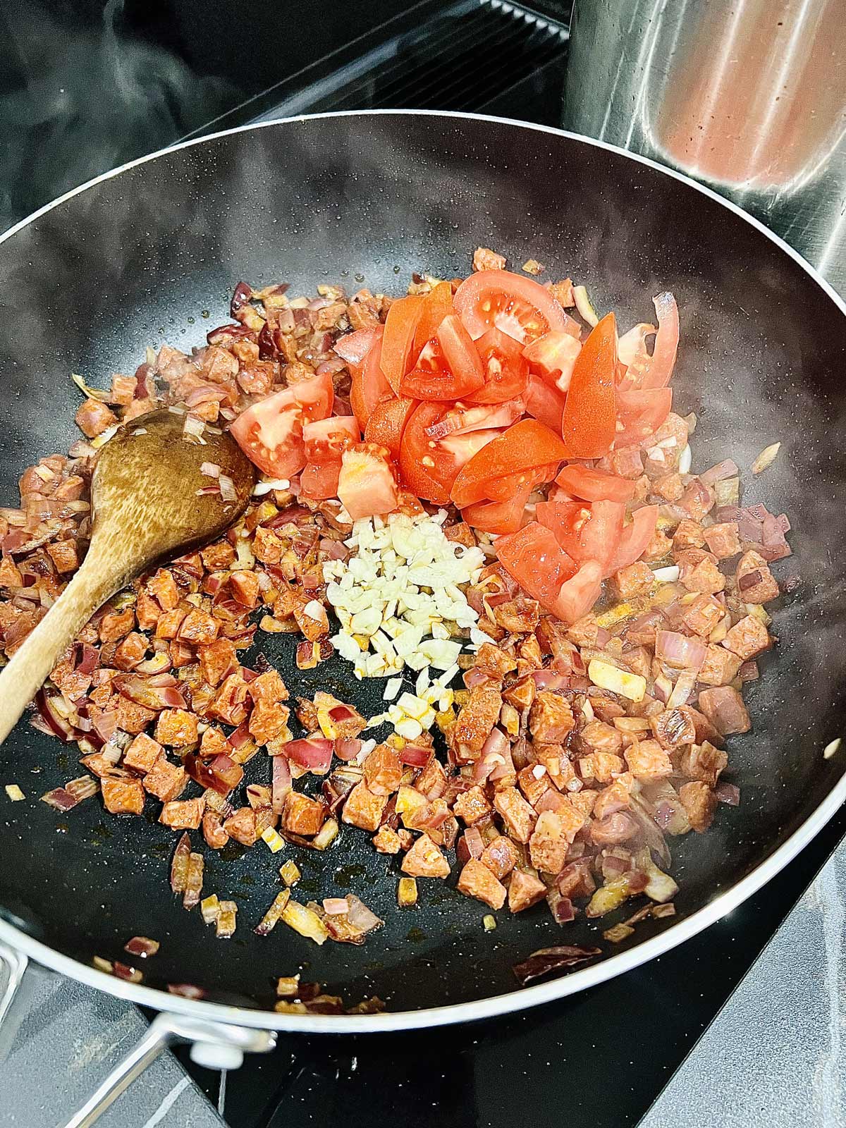 Chorizo, onion, garlic and chopped tomatoes cooking for prawn chorizo pasta dish.