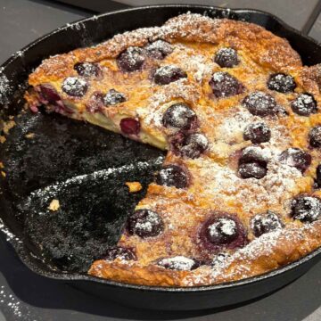 Clafoutis aux Cerises French dessert in a skillet, sliced up ready to serve.