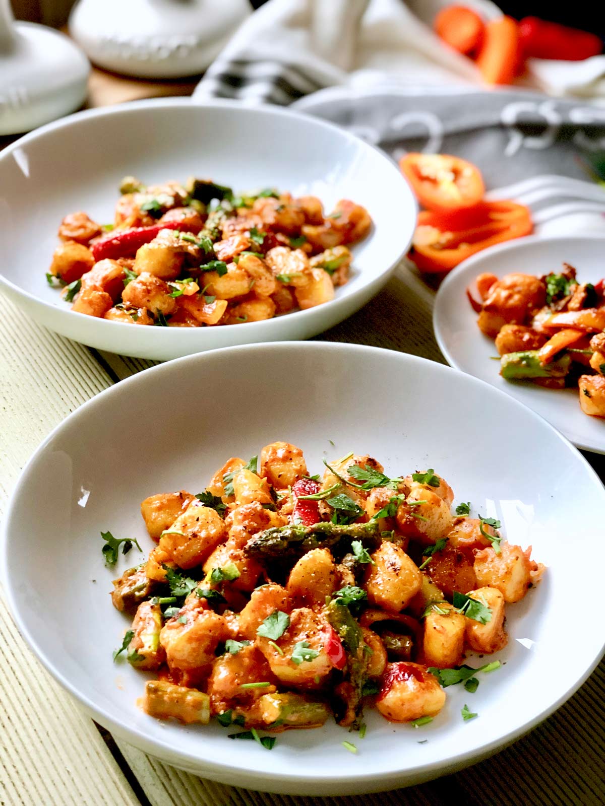 Easy Gnocchi Mascarpone with Asparagus on a white plate and fresh herbs sprinkled over.