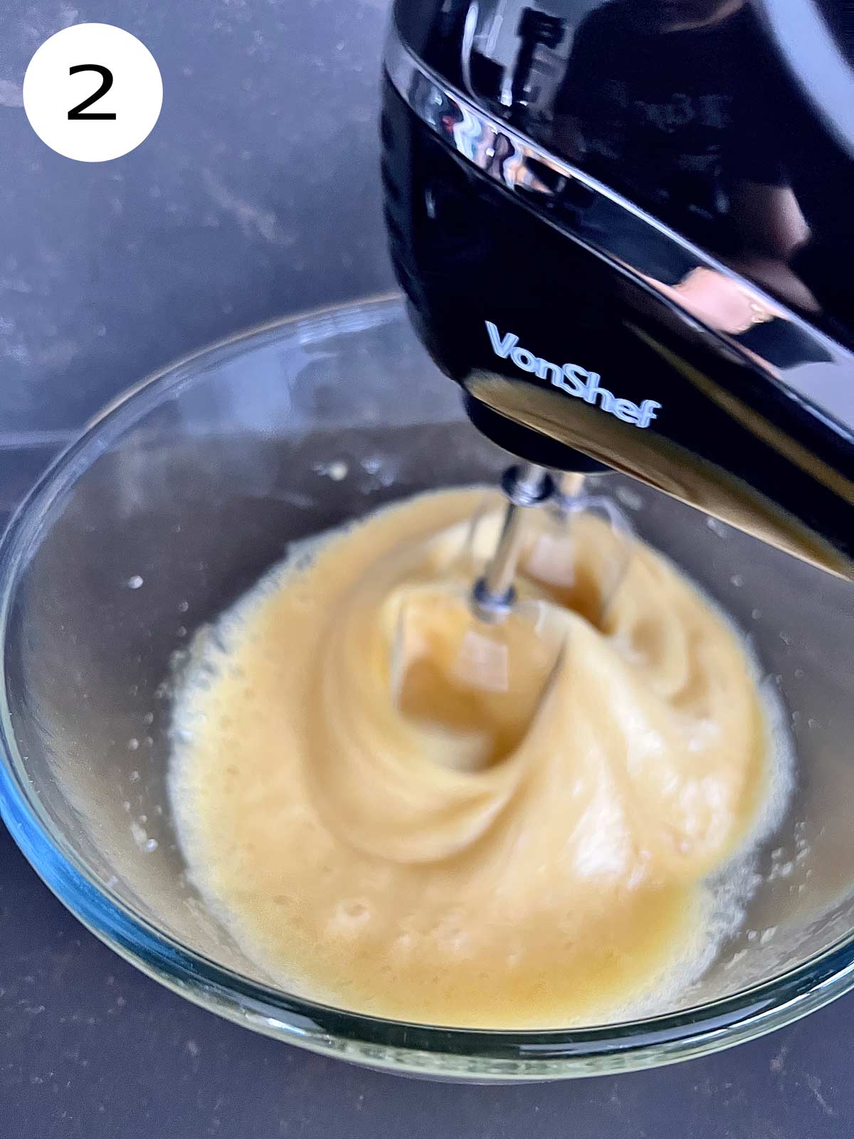 Eggs and sugar with salt being blended with a hand mixer.