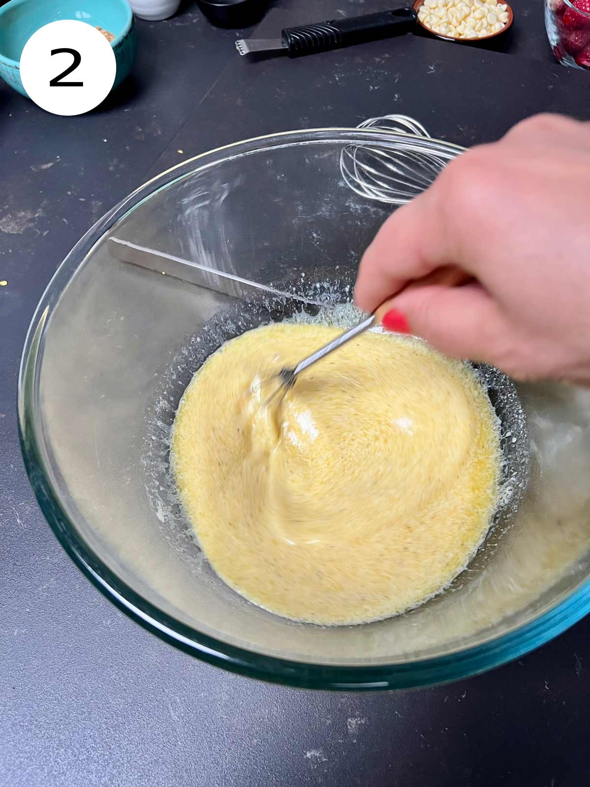 Eggs being whisked in a large glass bowl.