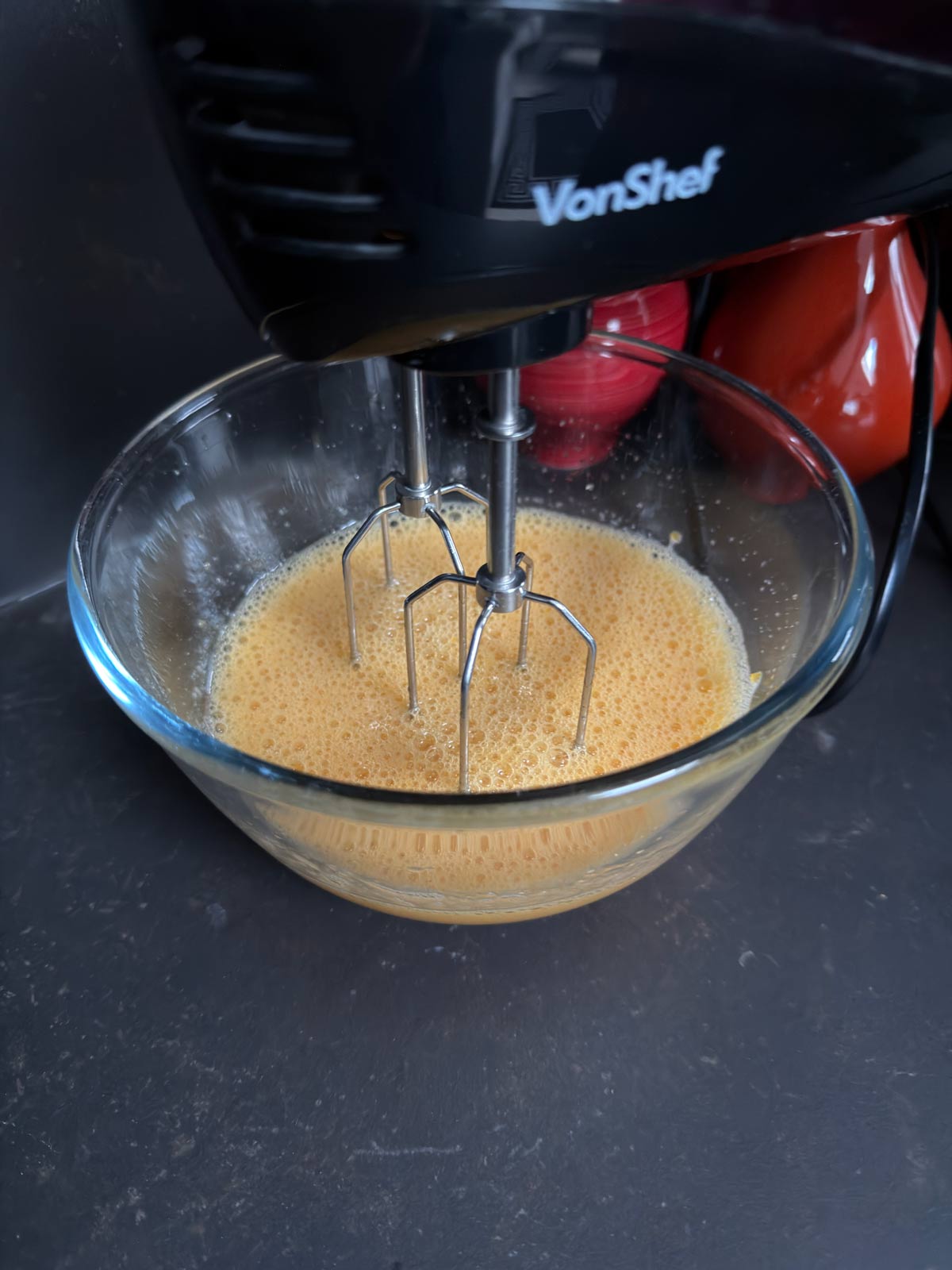 Eggs, sugar, and vanilla being mixed with a hand mixer.