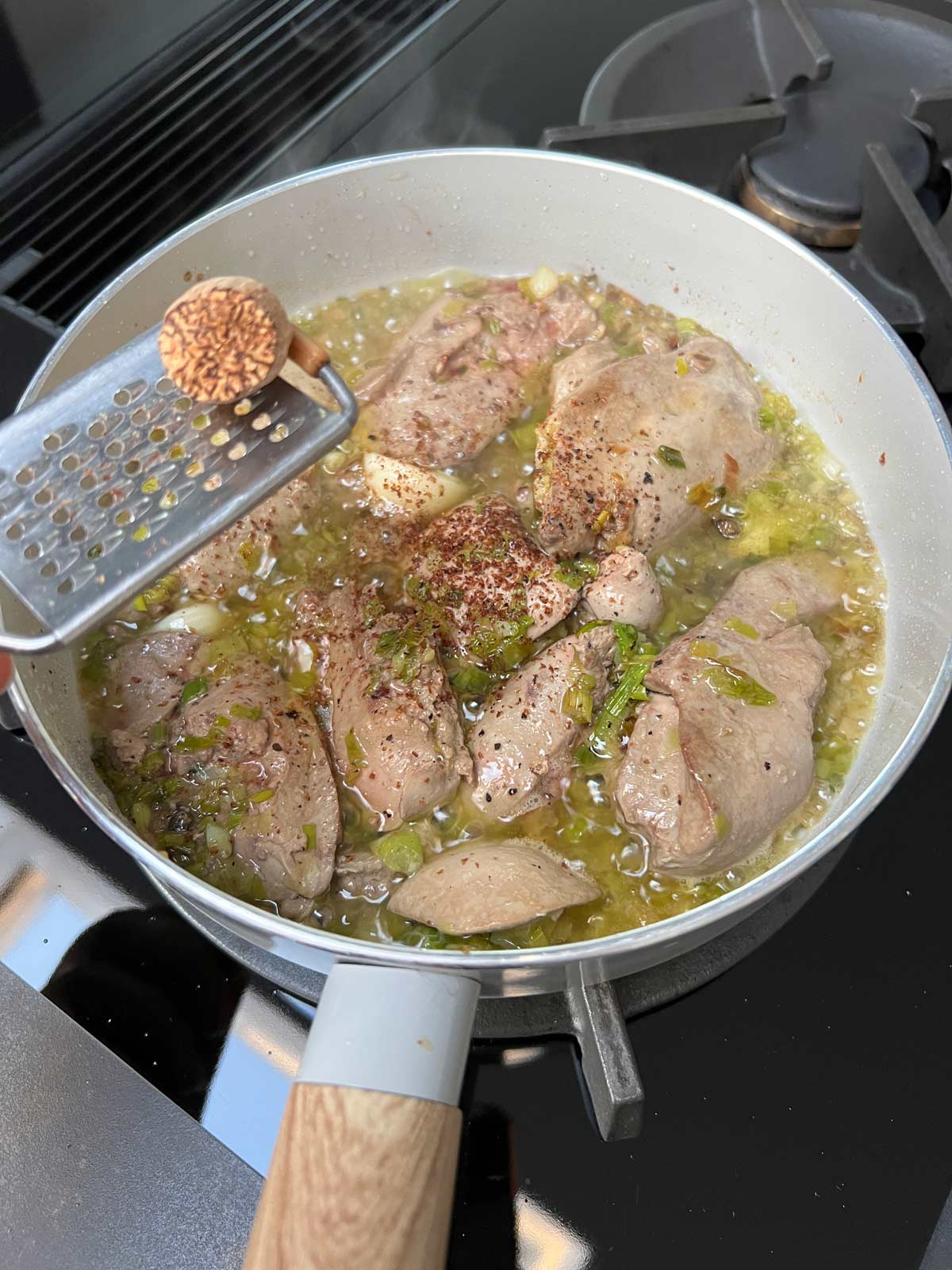 Grated nutmeg added to the pan containing most of the cooked chicken liver parfait ingredients.