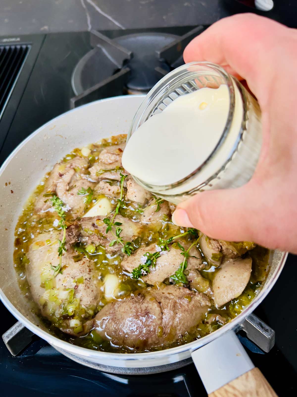 Heavy cream being added to a pan containing chicken liver parfait ingredients cooked to perfection.