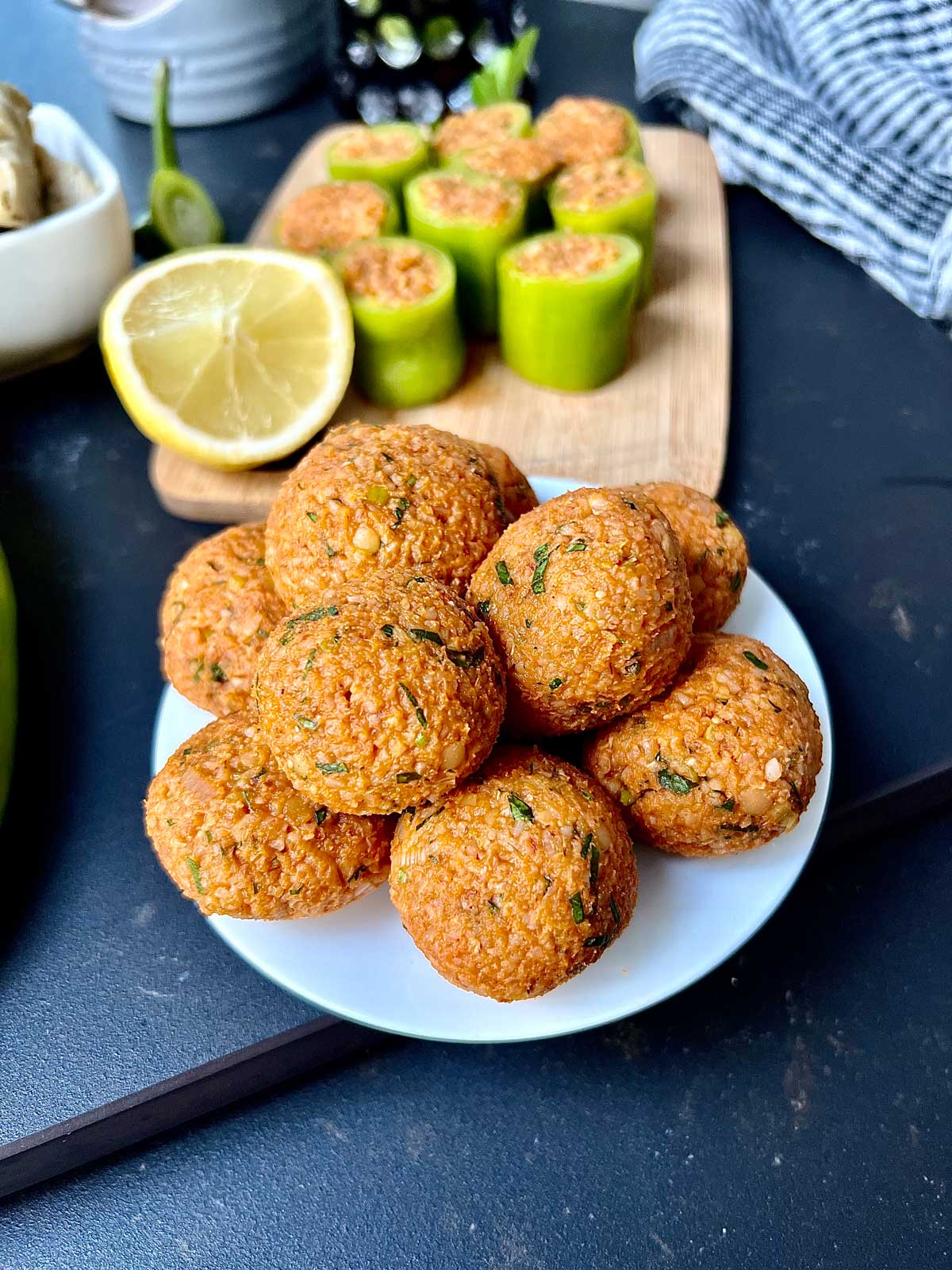 Vegan lentil balls on a little white plate on a granite plate with lemon on a side.