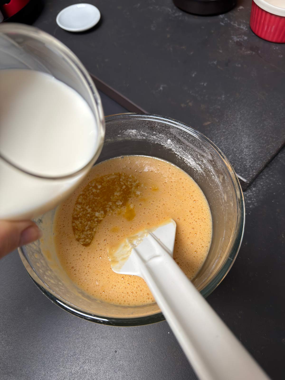 Milk and oil, added to the egg mix in the glass bowl.