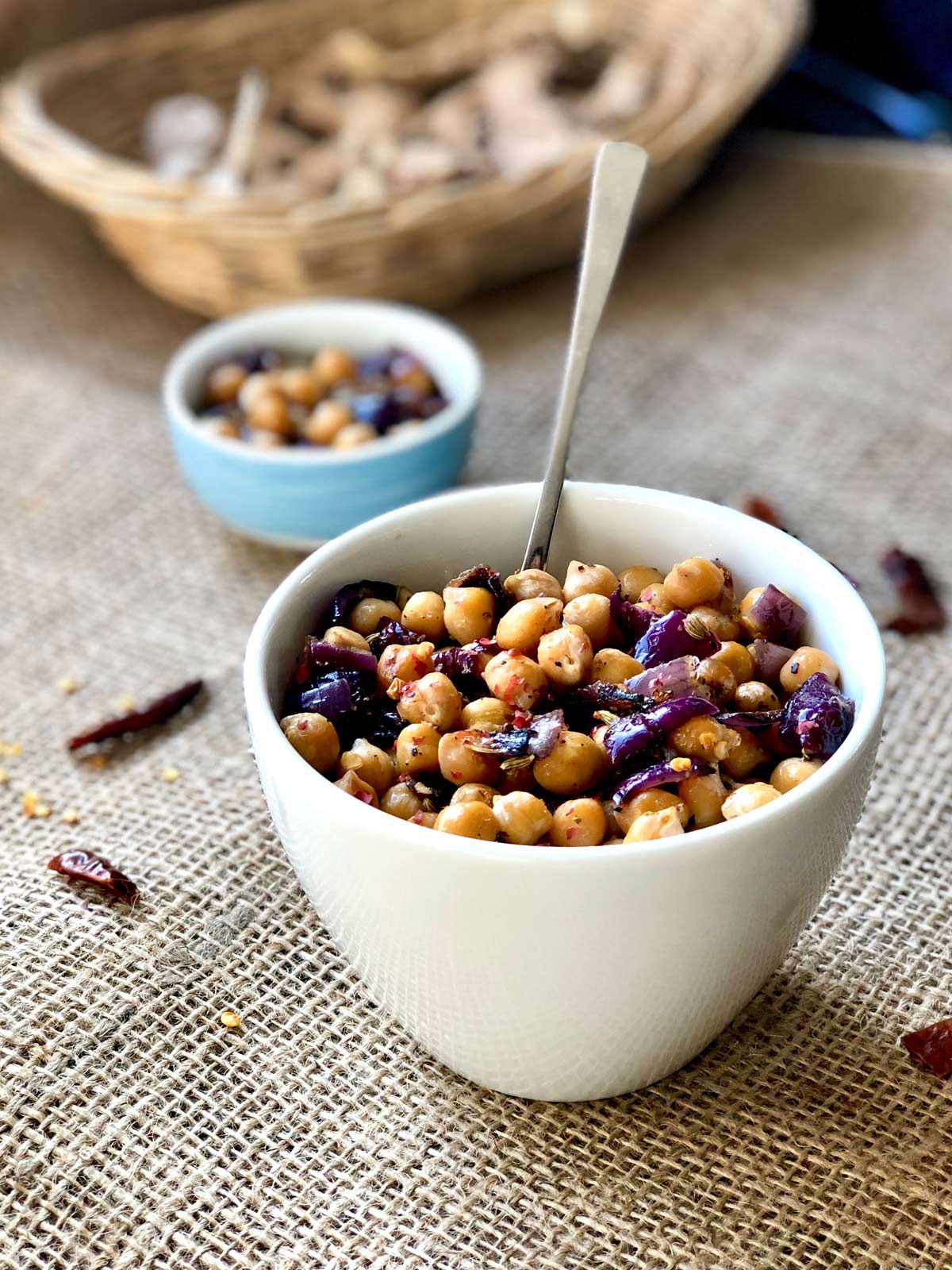 Sauteed chickpeas in a white serving bowl with a teaspoon tucked in.