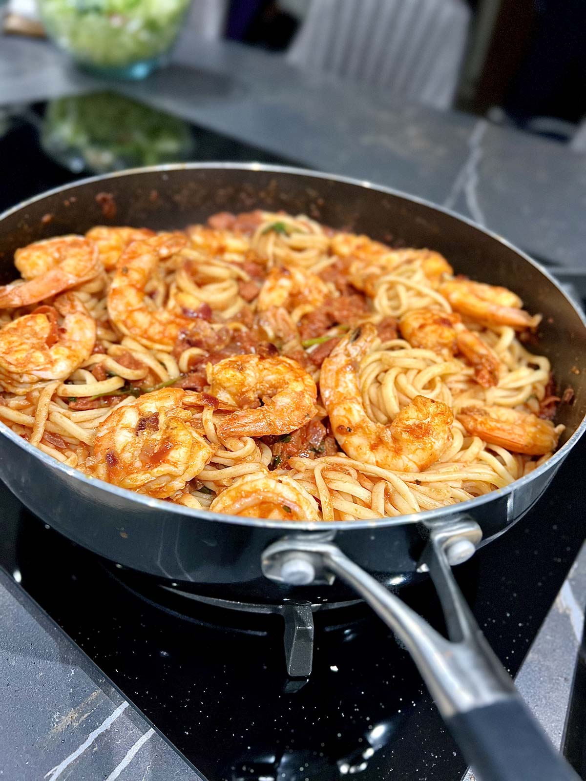 Shrimp and chorizo sausage pasta dish in a black pan.