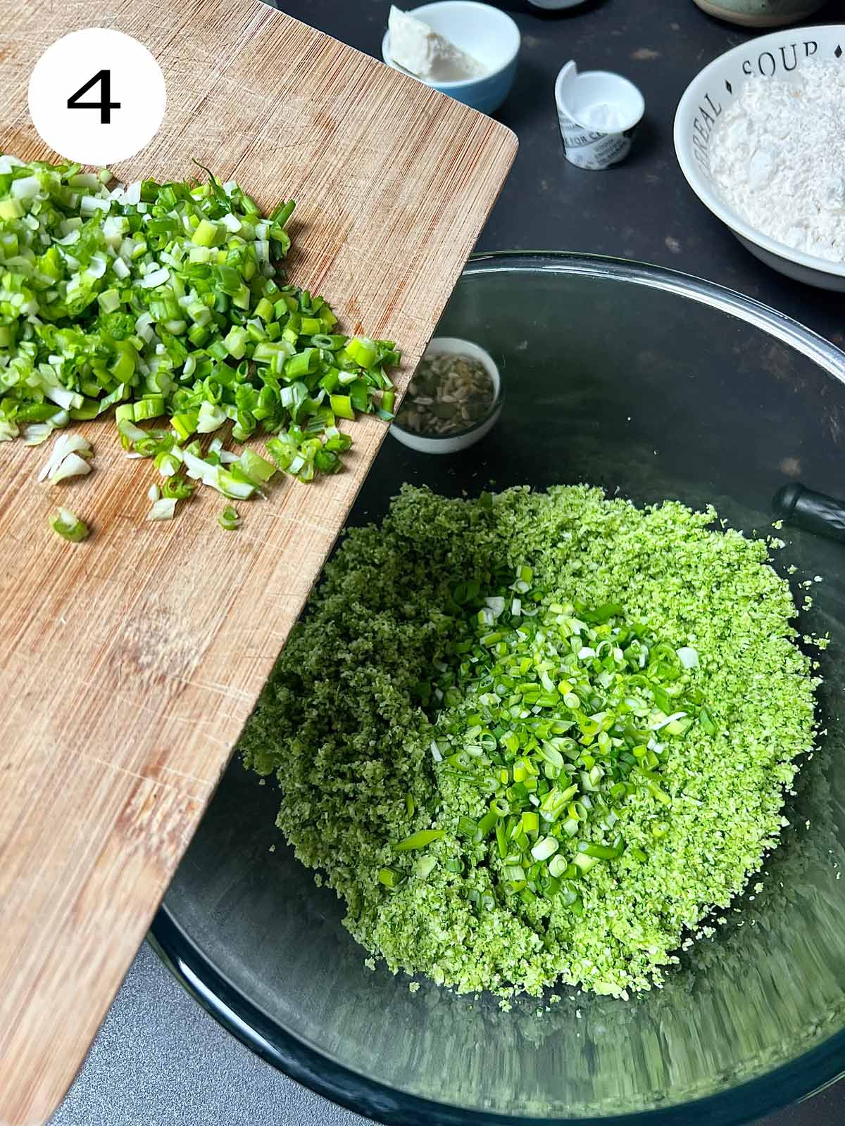 Spring onion/scallions being added to the blended broccoli into a big glass bowl.