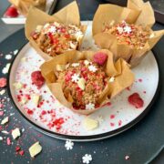 Three raspberry and white chocolate muffins on a white plate.