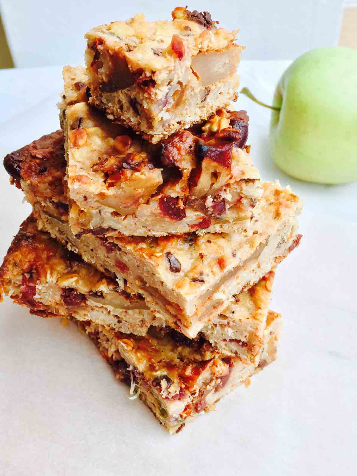 A tower of apple baked oats slices on a white surface.