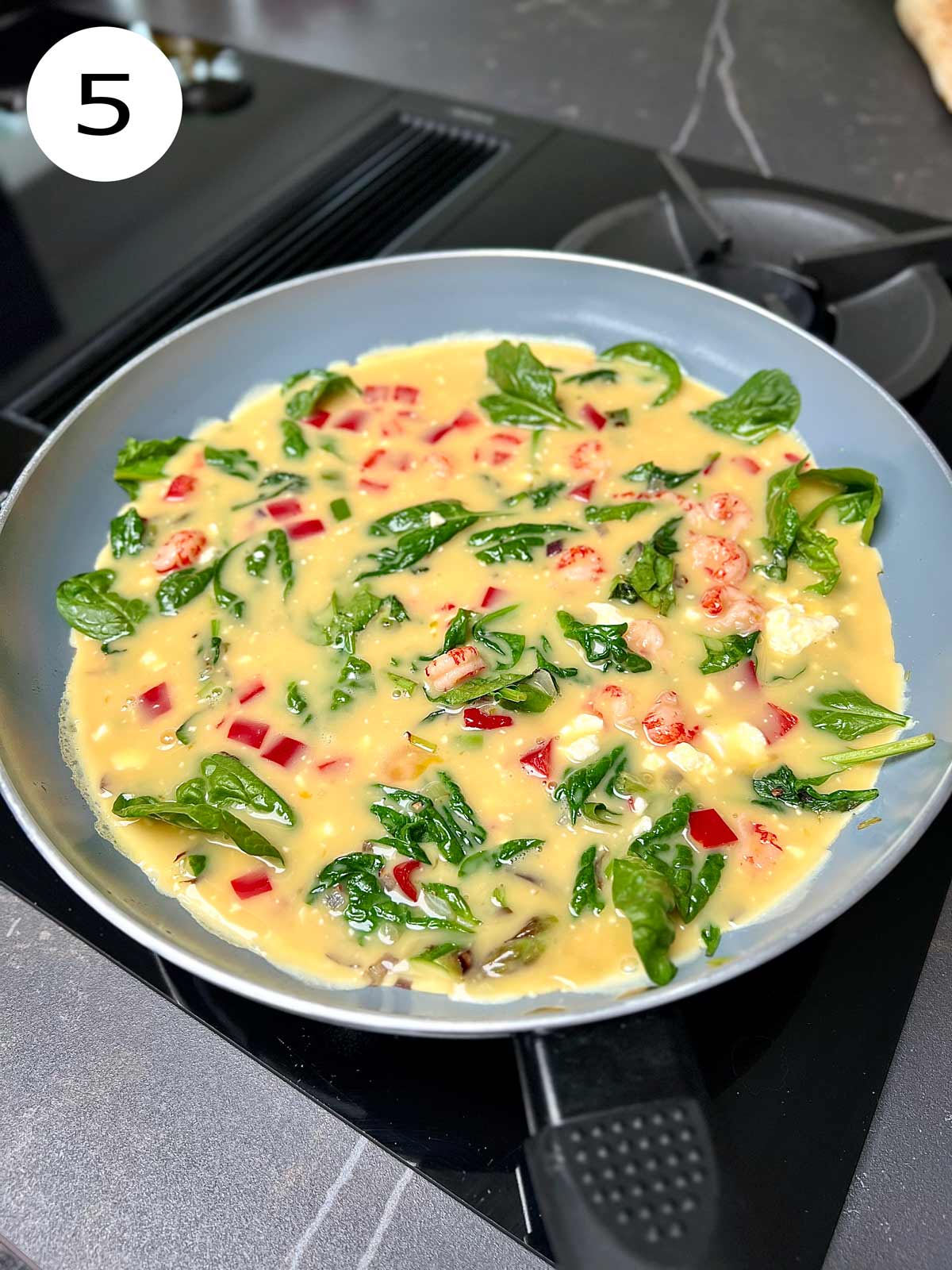 Beaten eggs and red pepper poured over the sautéed vegetables.