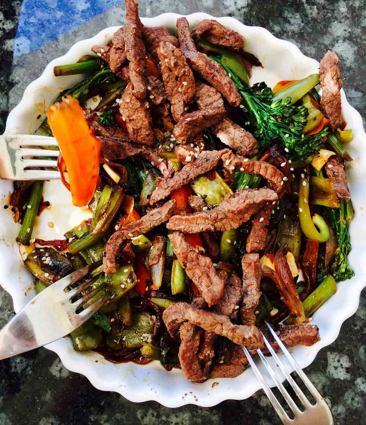 Beef hoisin stir fry with tenderstem broccoli, carrot and green pepper on a white plate