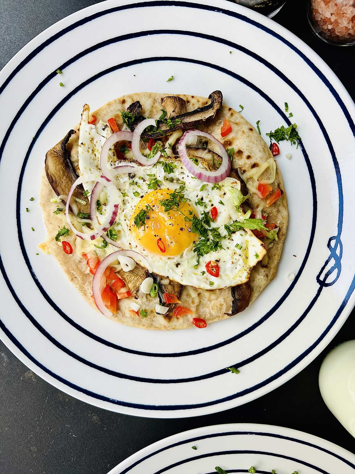 Birds view of a tortilla and egg on a white plate with dark circular rings pattern.