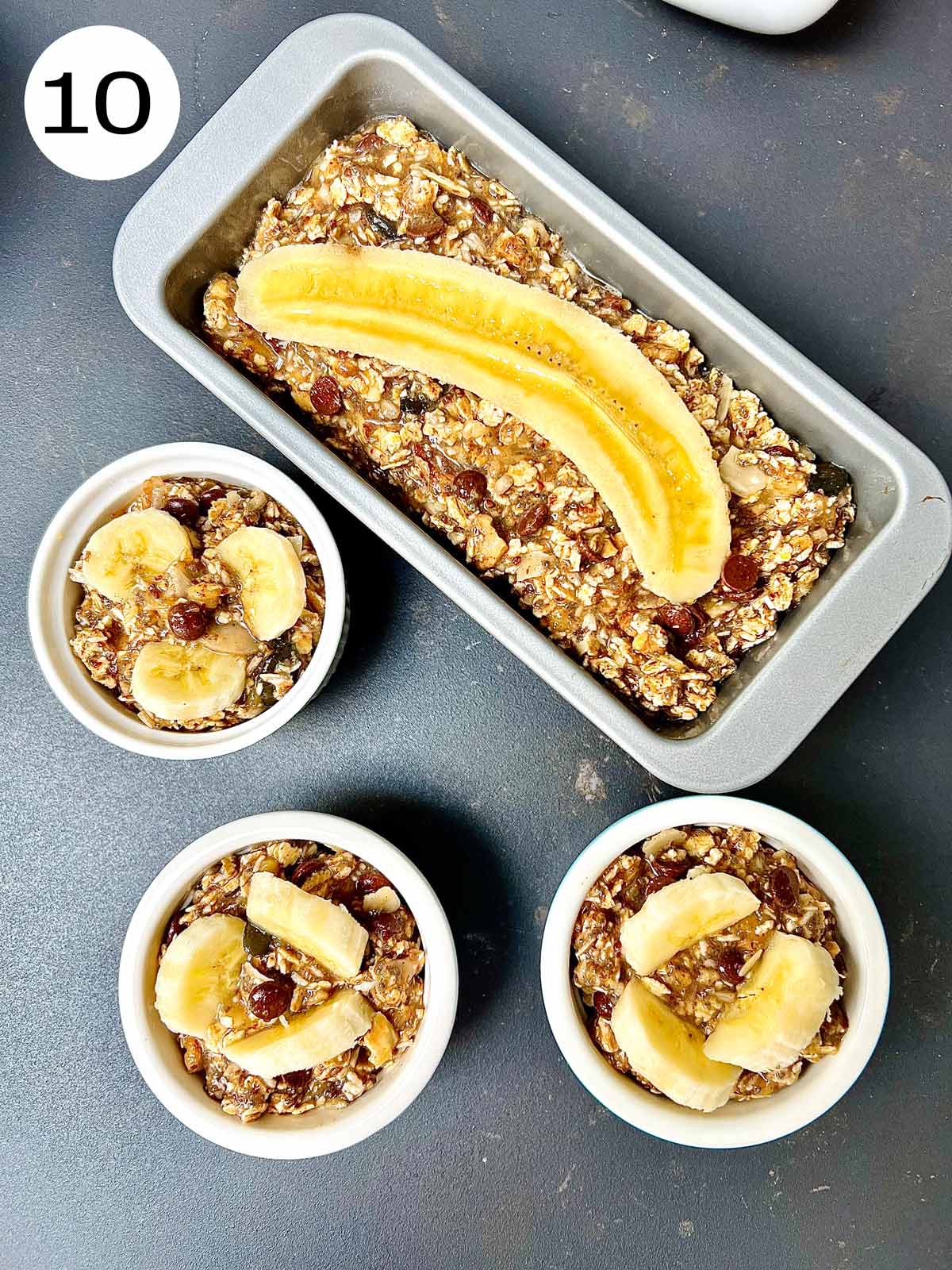 Bread tin filled with banana mixture and 3 ramekins topped with banana slices ready to go in the oven.