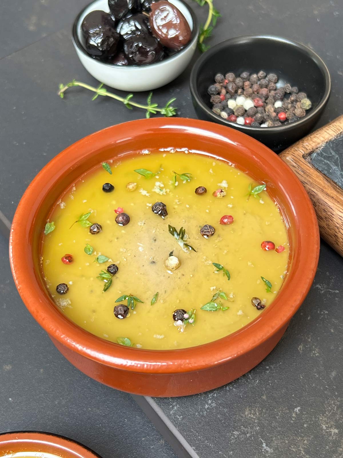 Chicken liver parfait topped with melted butter, peppercorns and fresh herbs ready to go in refrigerator for cooling.