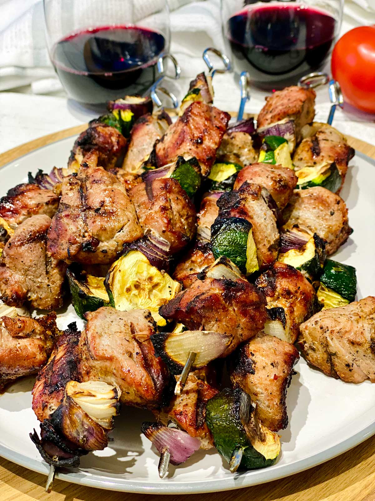 Chicken skewers baked in the oven on a white plate over a wooden finished plate