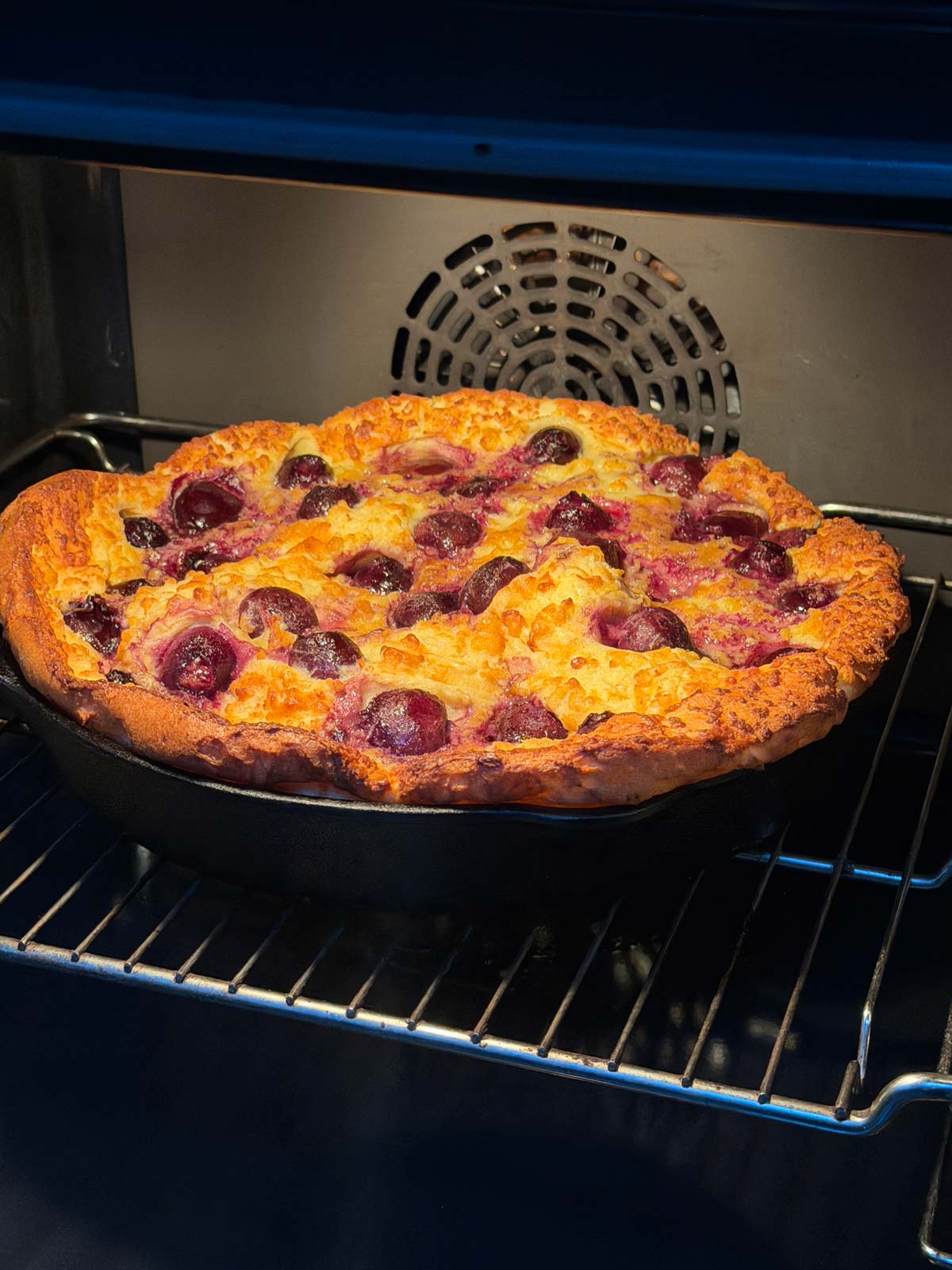 Puffed up clafoutis in the oven, nicely browned.