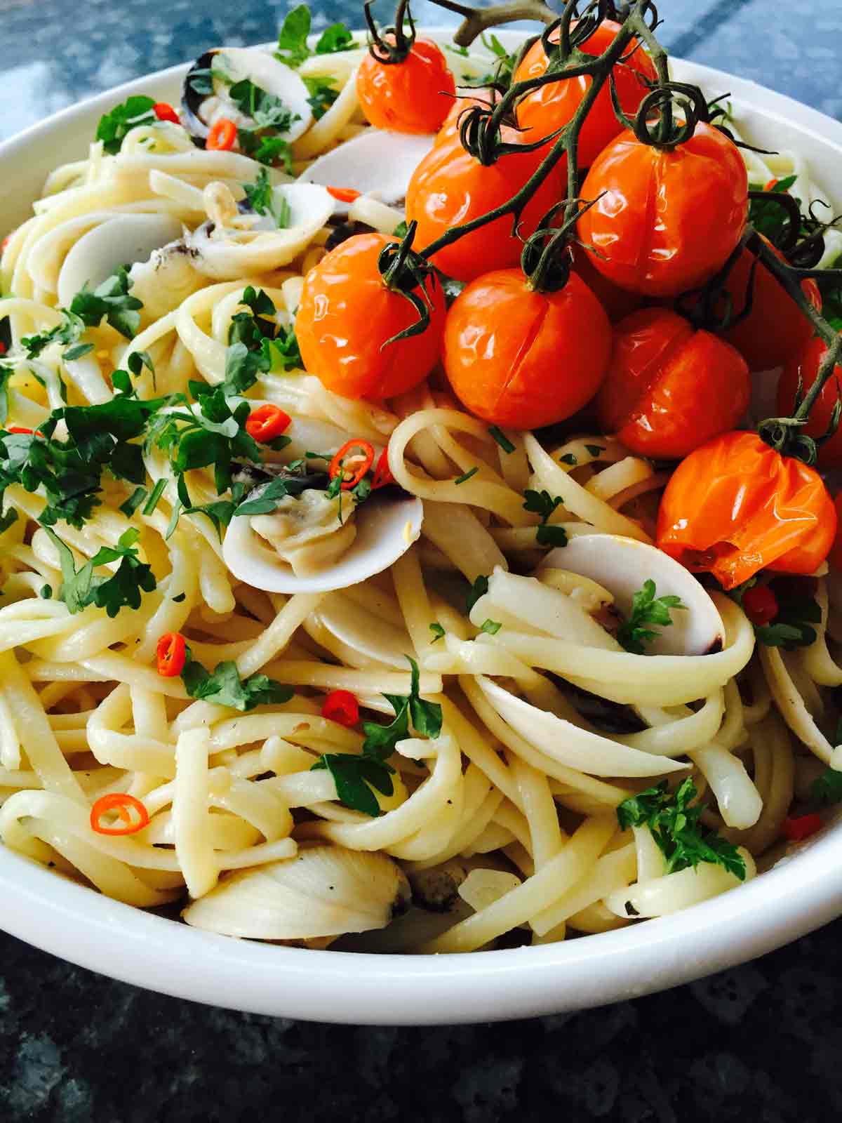  Linguini pasta with clams and calamari, and fresh parsley, close up.