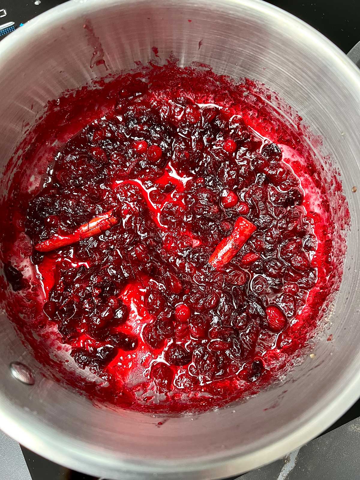 Small batch of cranberry jam with cinnamon sticks ready to be jarred.