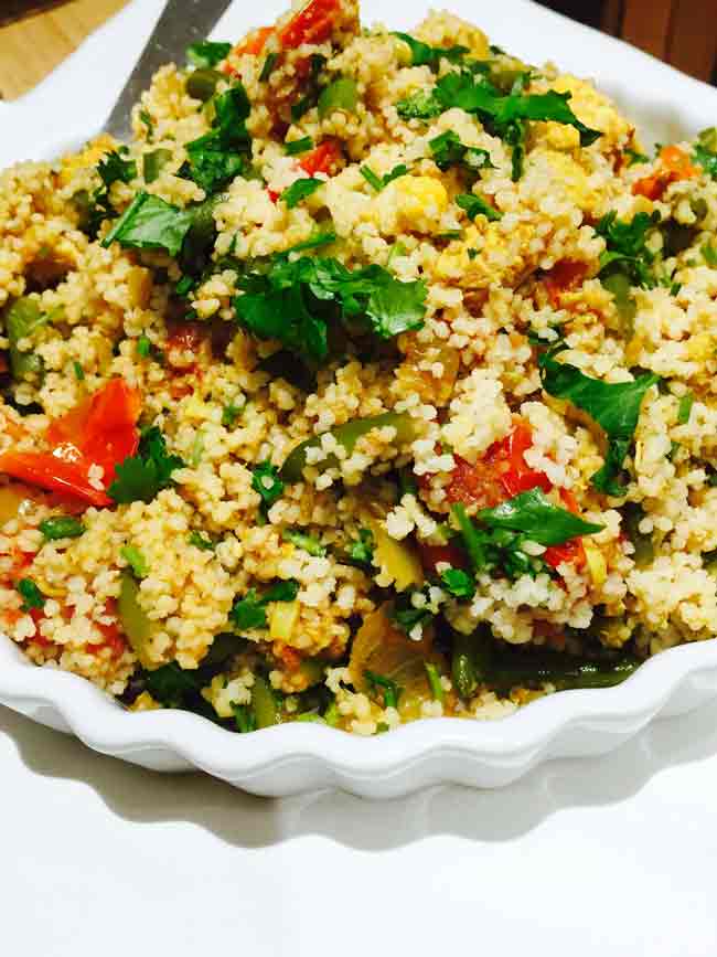 A close-up of a white plate with curried chicken couscous