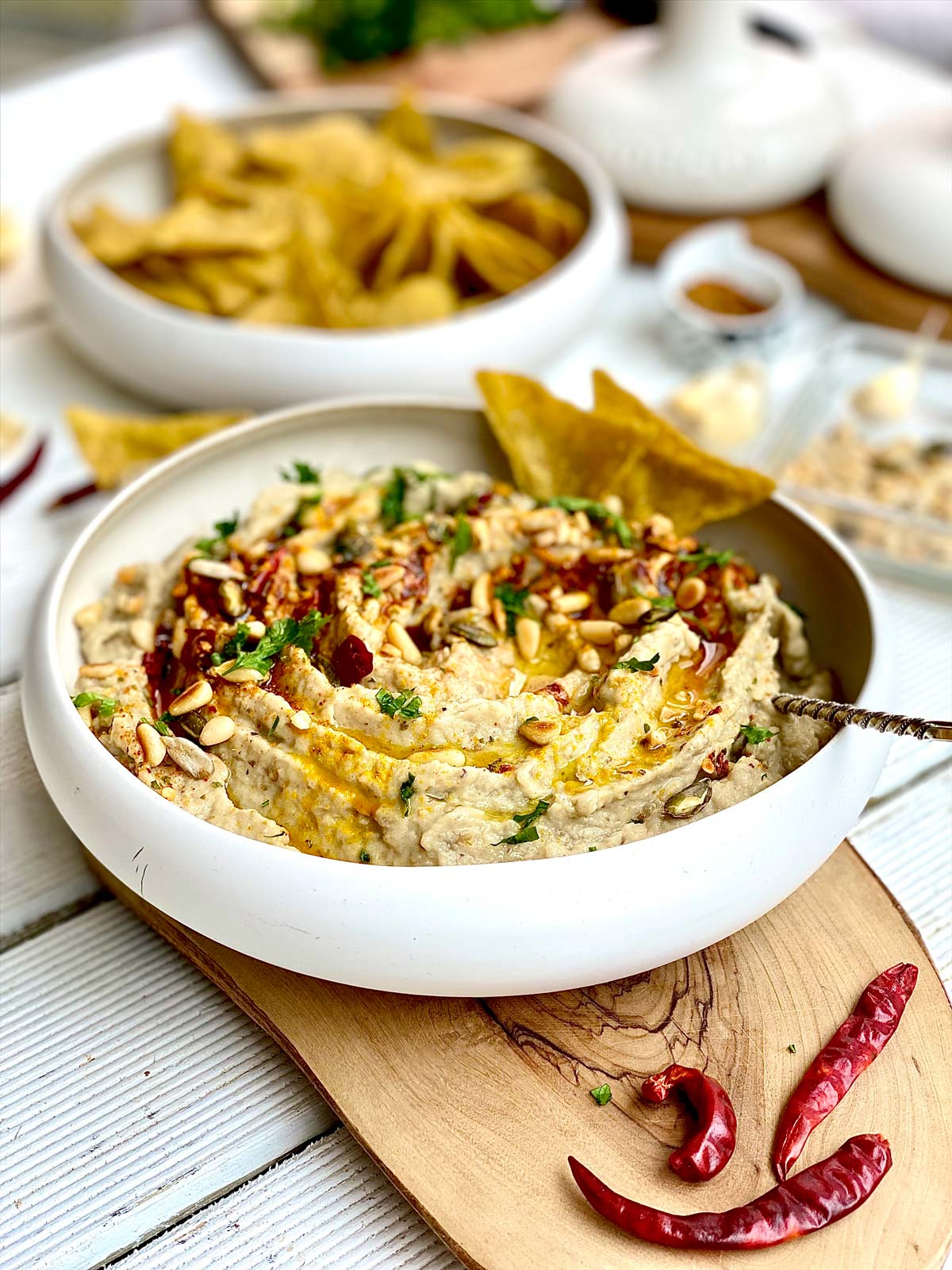 Close up of creamy eggplant dip topped with paprika, seeds and fresh herbs and olive oil