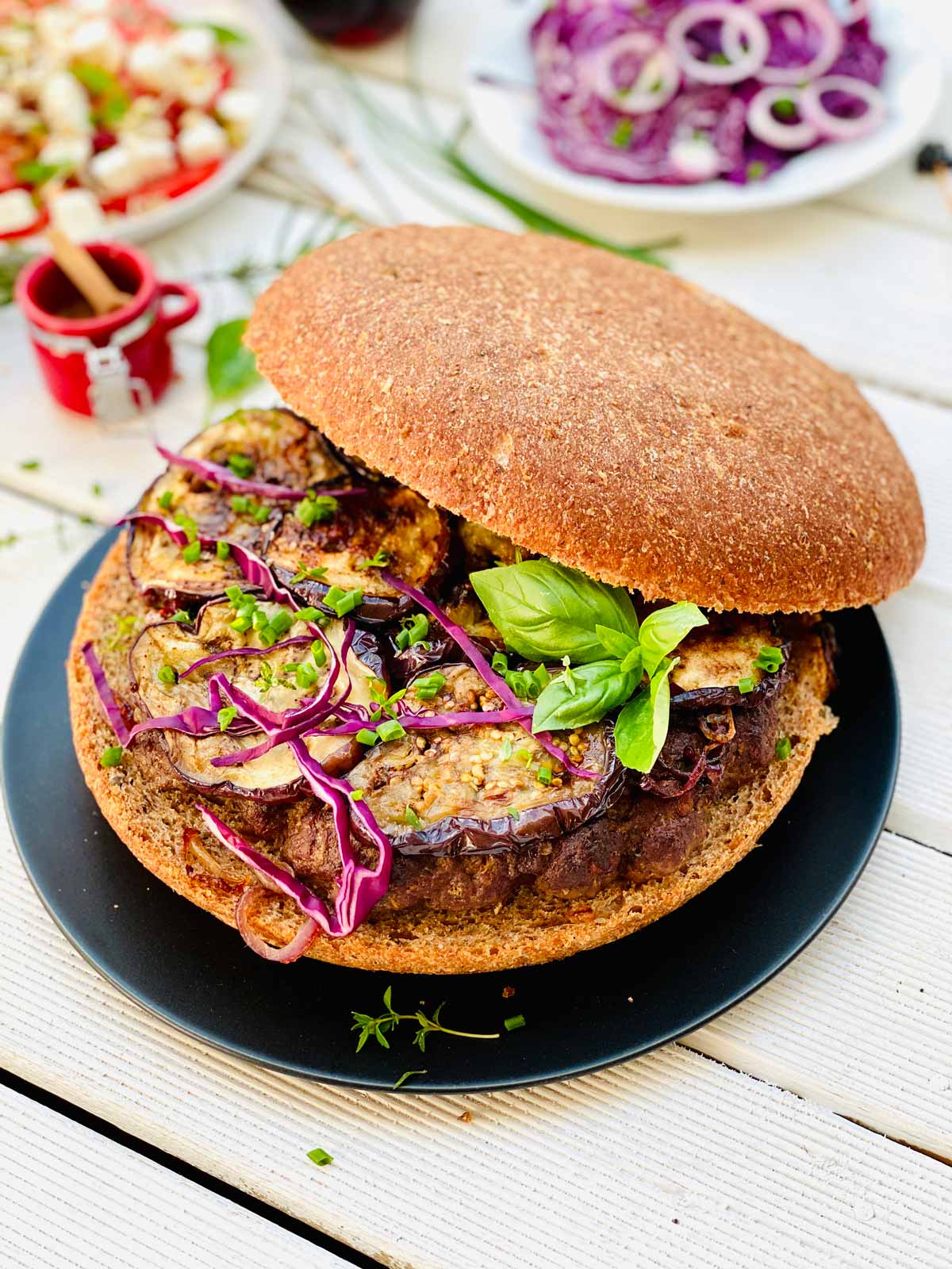 Giant Lamb Burger with Miso Aubergines on a Black Plate