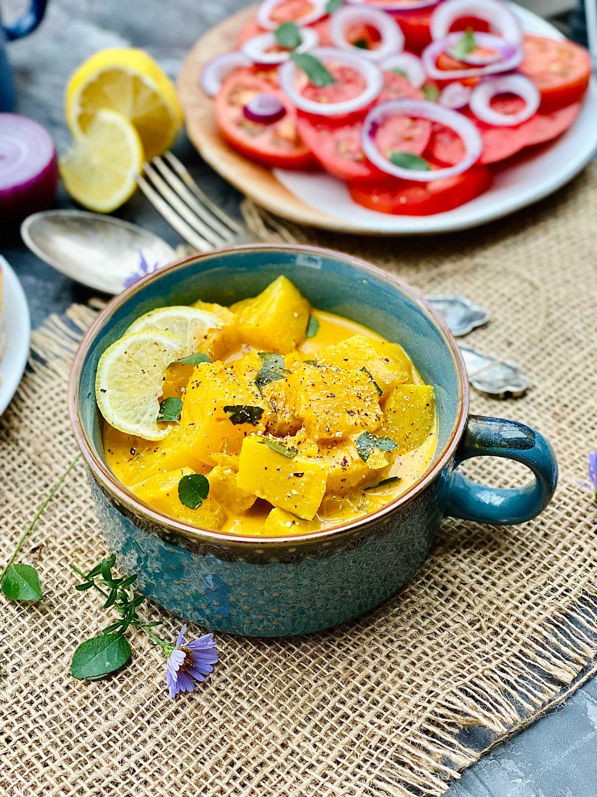 Pineapple curry in a green ceramic pot sprinkled with black pepper and curry leaves