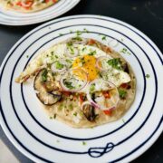 Egg on tortilla ready to be served and sprinkled with fresh herbs and some red onion rings.
