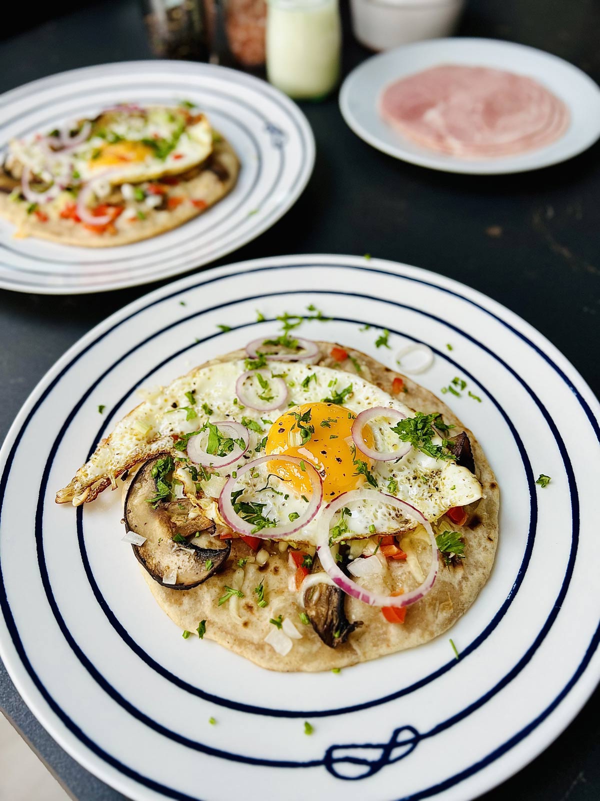 Egg on tortilla ready to be served and sprinkled with fresh herbs and some red onion rings.