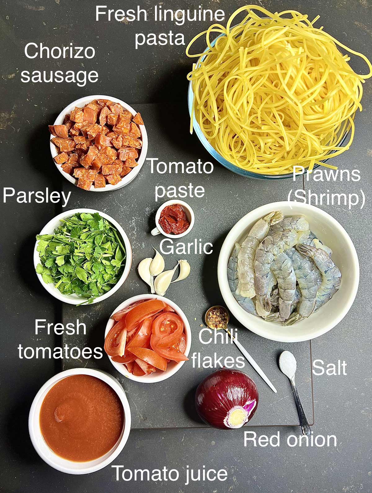 Ingredients needed (chorizo, fresh pasta, parsley, tomato paste, garlic prawns, fresh tomatoes, salt, red onion, tomato juice) for the prawn and chorizo pasta.
