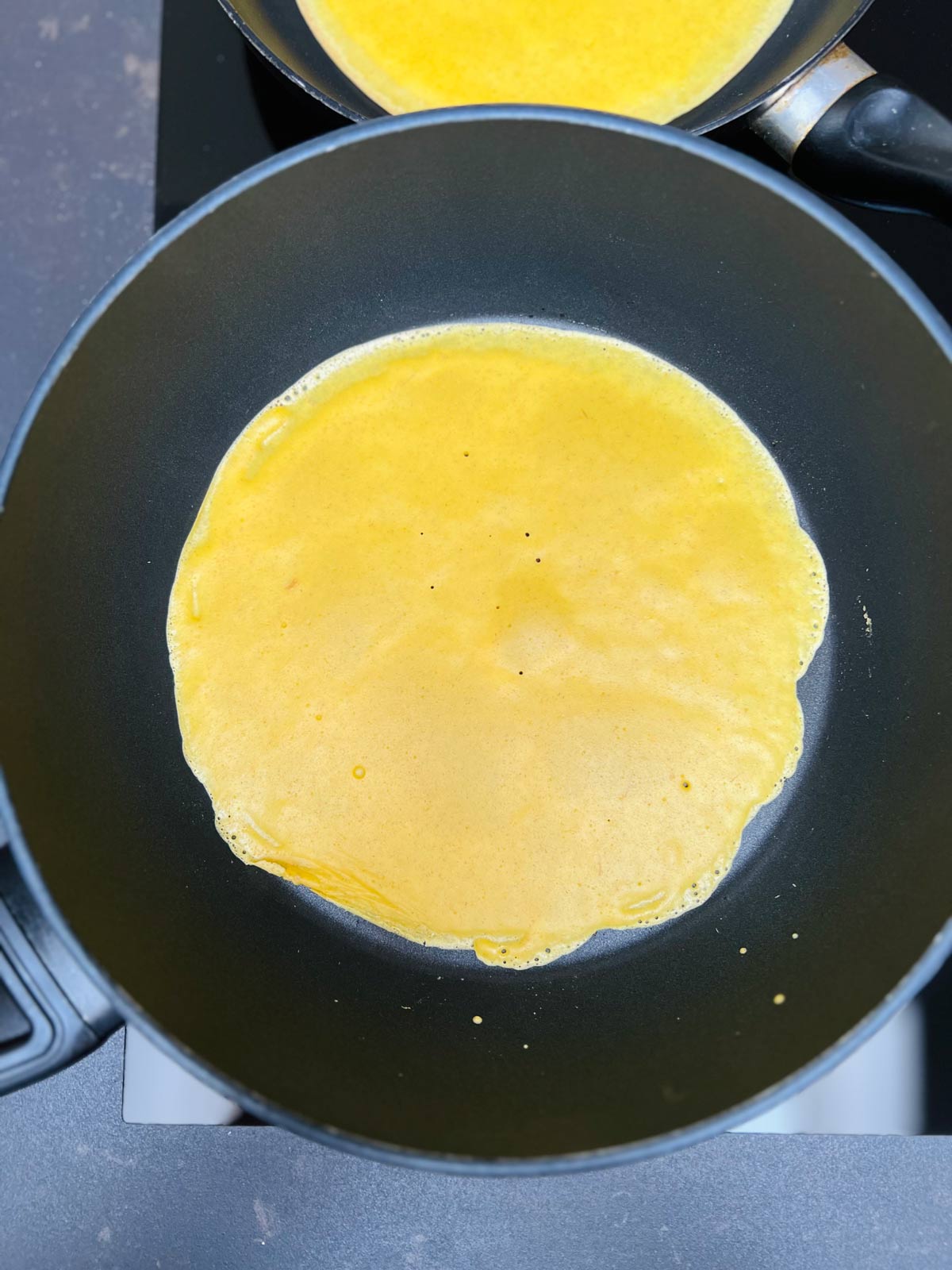 Bright, yellow pancake, cooking in a pan.