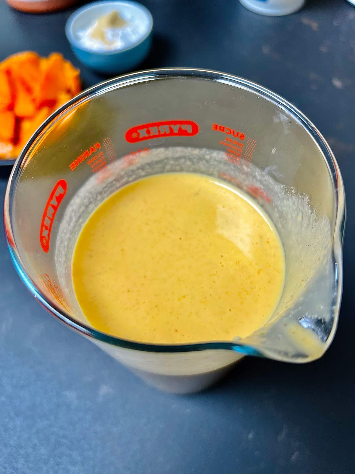 Mango pancakes batter in a measuring jug.