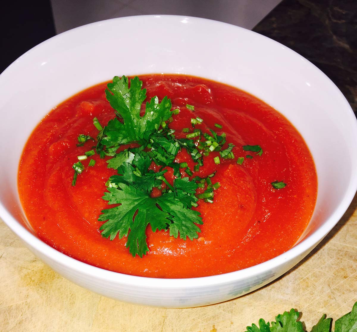 Morrocan tomato and cauliflower soup in a white ceramic bowl with some fresh parsley scattered over the top of the soup.