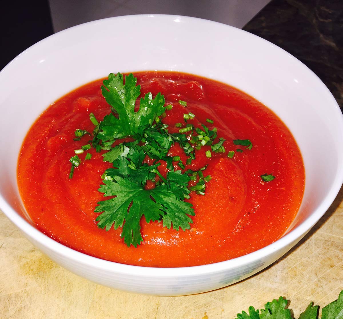 Morrocan tomato and cauliflower soup in a white ceramic bowl with some fresh parsley scattered over the top of the soup. 