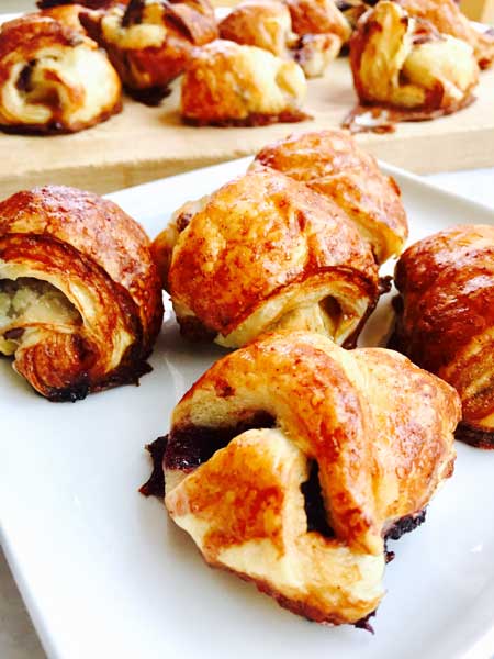 A close-up of a white plate with banana, cherries and nutella puffs.