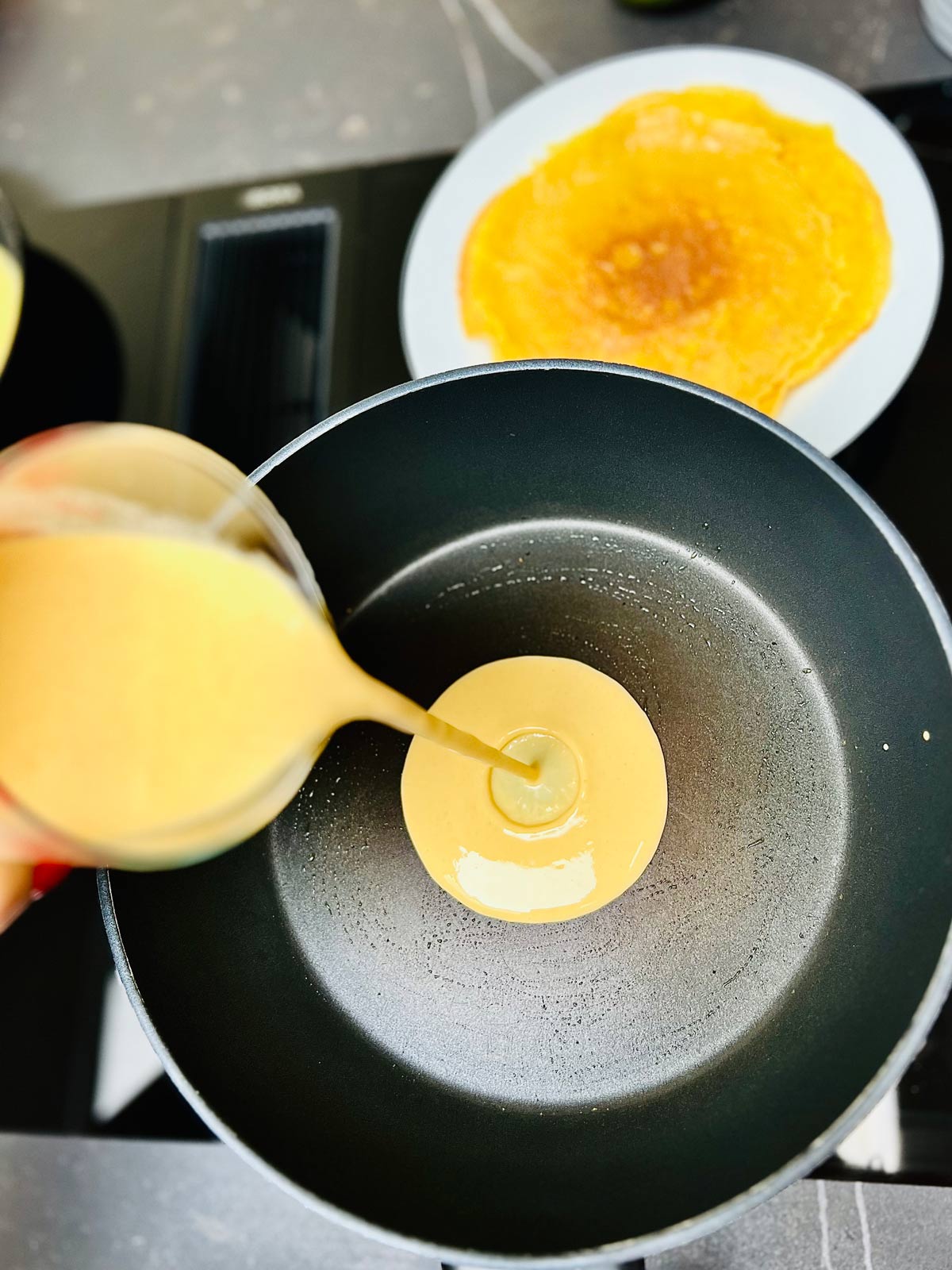 Pancake batter being poured in the pan ready to be cooked.