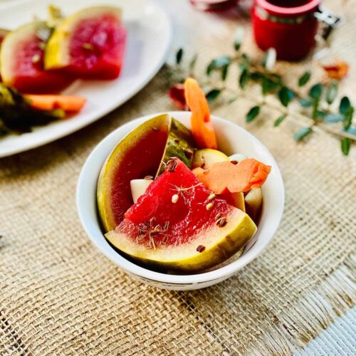 Pickled watermelon quarter slices with pickled carrot in a white serving dish