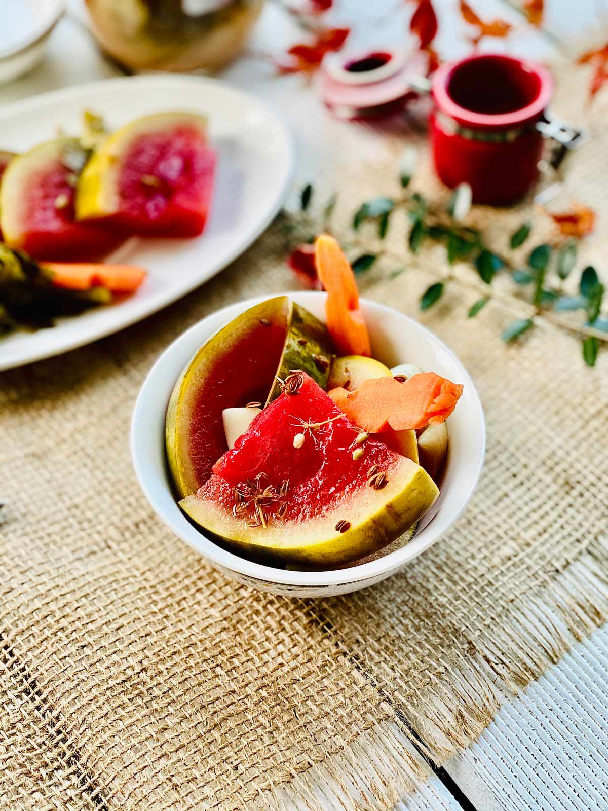 Pickled watermelon quarter slices with pickled carrot in a white serving dish