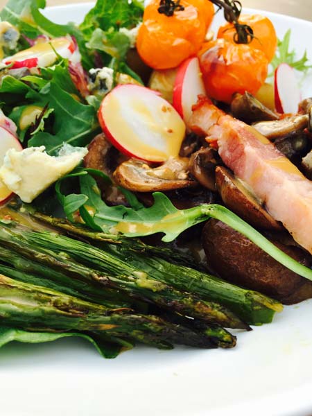 A close-up of the delicious potato roast, with a small arrangement of grilled asparagus and cherry tomatoes.