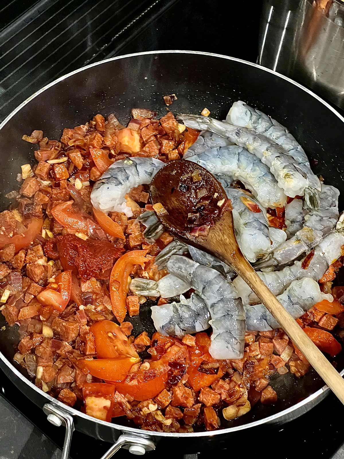 Prawn and tomato paste added to the pan where chorizo, onion, garlic, fresh tomatoes were cooking for this prawn and chorizo pasta dish.