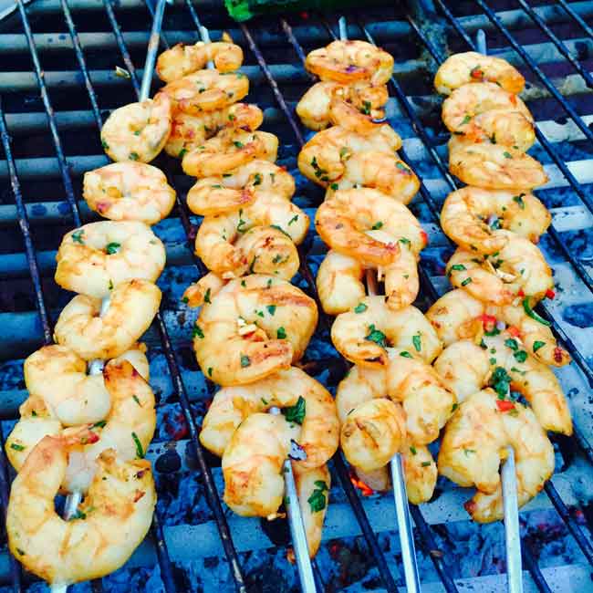 4 skewers with prawns, on a grill