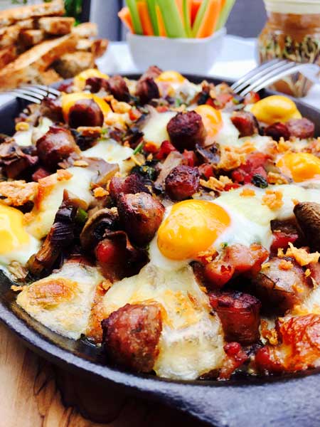 A close-up of the skillet full of quail eggs, mushrooms and bacon.